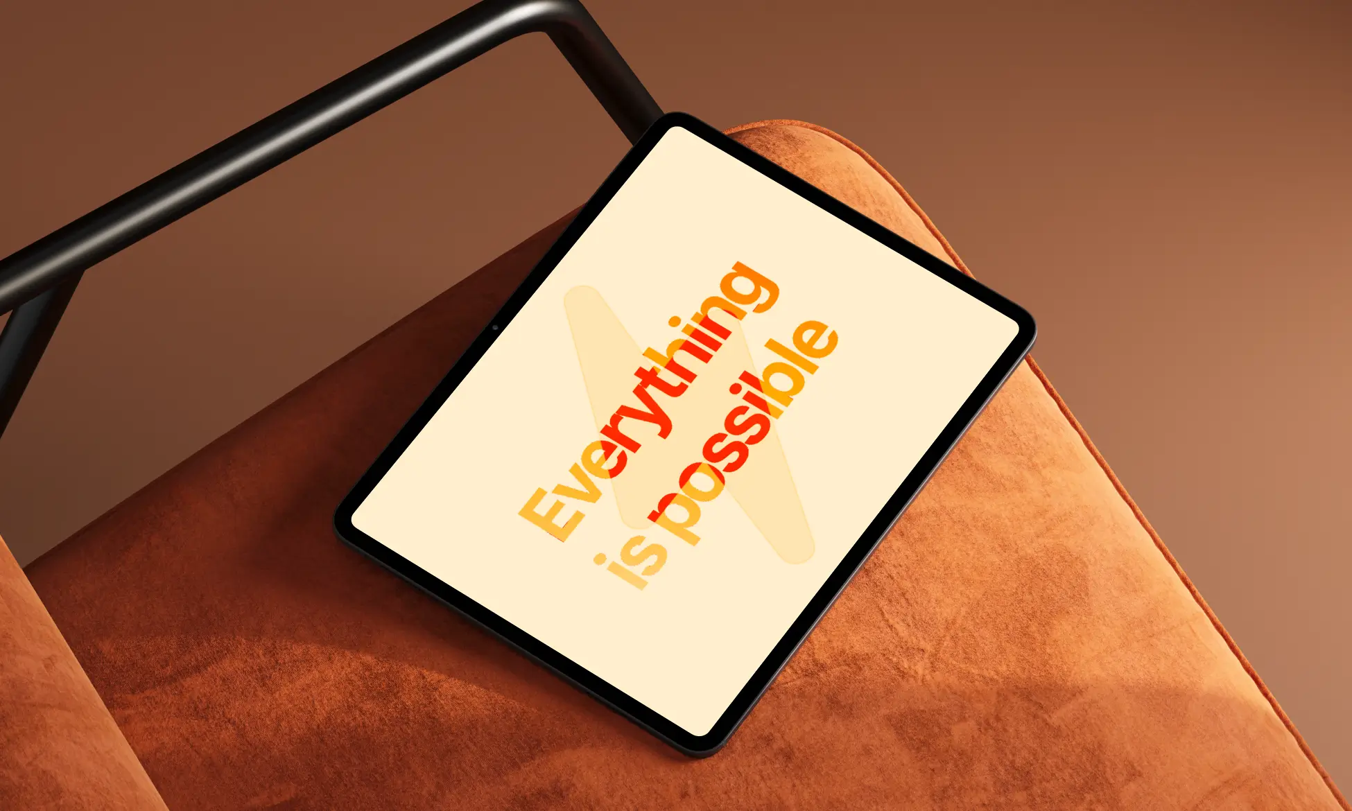 Tablet resting on an orange sofa, screen shows the orange text 'Everything is possible'.
