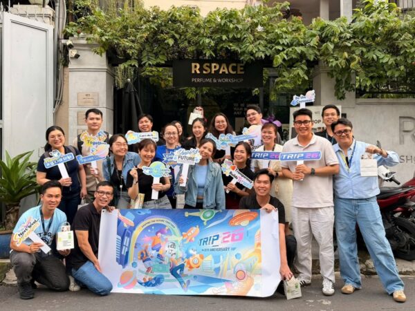 Group of people posing outside a shop holding colorful event signs for Trip 26.