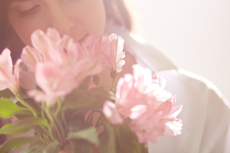 Woman smelling a bouquet of pink flowers in soft focus close-up