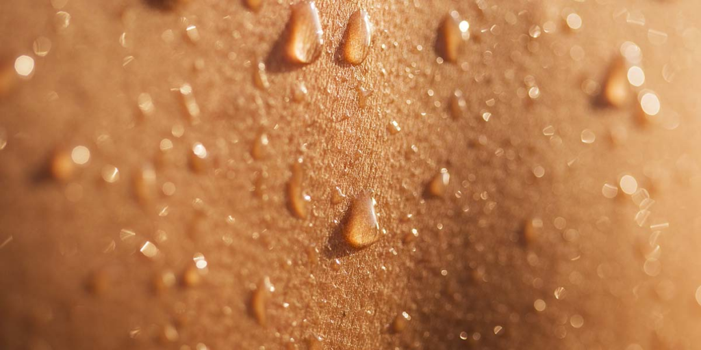 Close-up of shiny sweat beads on textured brown skin (macro photography)
